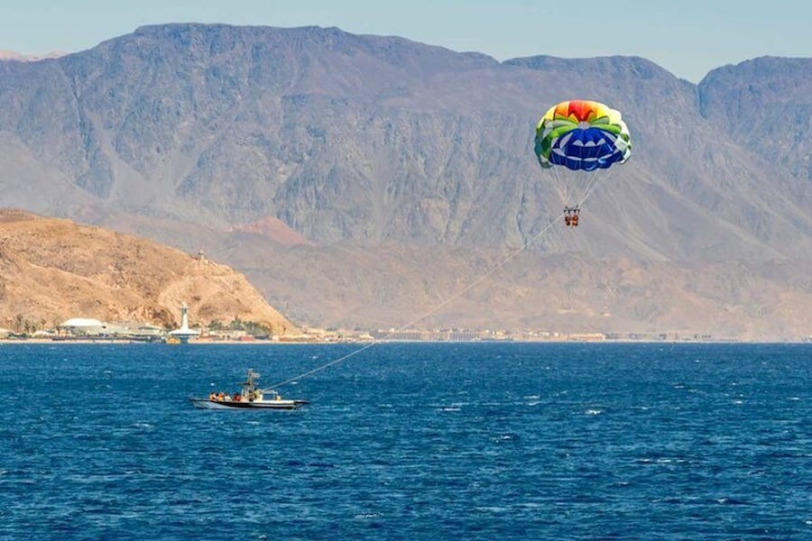 Barca del parasailing con paracadute in volo sopra le acque cristalline di Sharm El Sheikh.